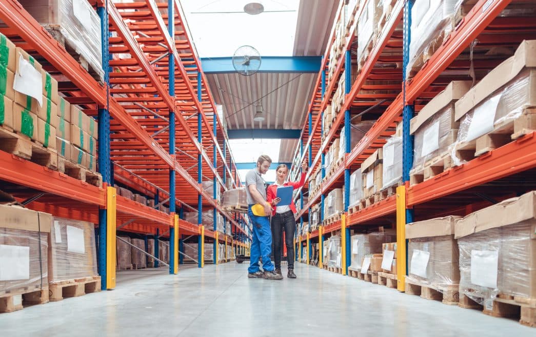 Warehouse staff picking orders in a long aisle of stocked racks