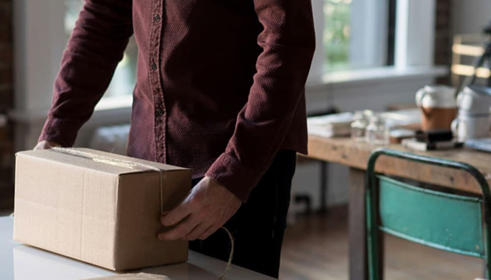 Person packing a cardboard box of inventory for shipment