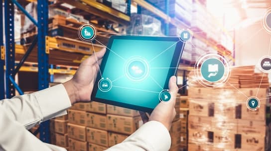 Hands holding a tablet in a warehouse aisle, with connected inventory icons overlaid