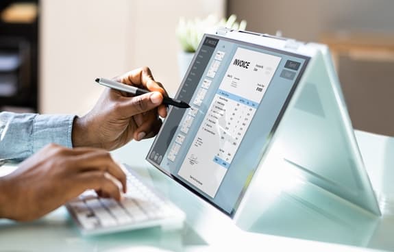 Person comparing a shipping invoice on a tablet while typing