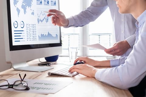 Two colleagues reviewing warehouse analytics charts on a desktop monitor